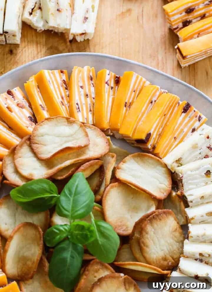 White round plate filled with cheese appetizers with crackers and garnished with basil.