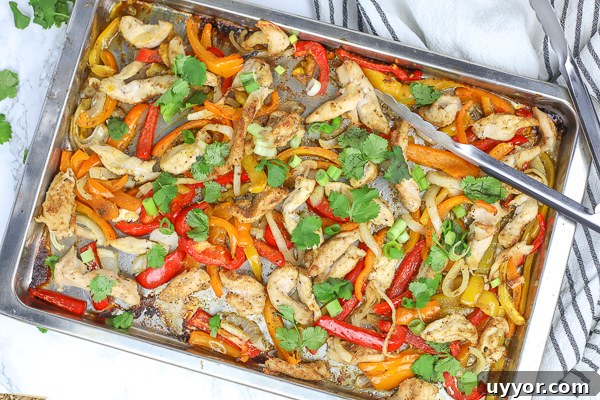 sheet pan chicken fajitas with cilantro on a counter with a striped towel