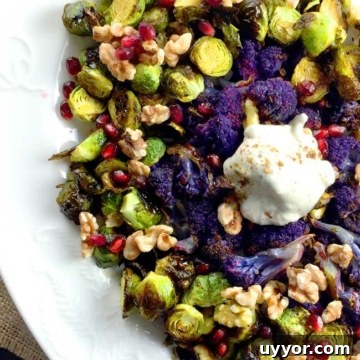 Crispy Roasted Brussels Sprouts with Pomegranate Molasses Glaze 8 roasted brussels sprouts with yogurt topping and purple cauliflower on a white plate