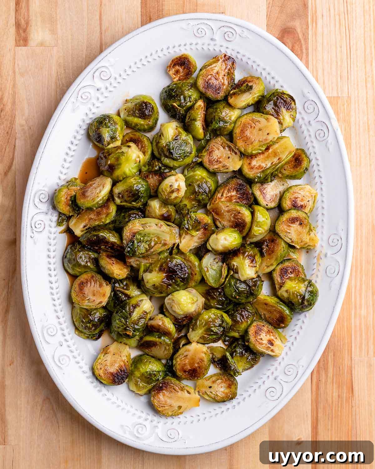 Roasted brussels sprouts in oval white plate on table.