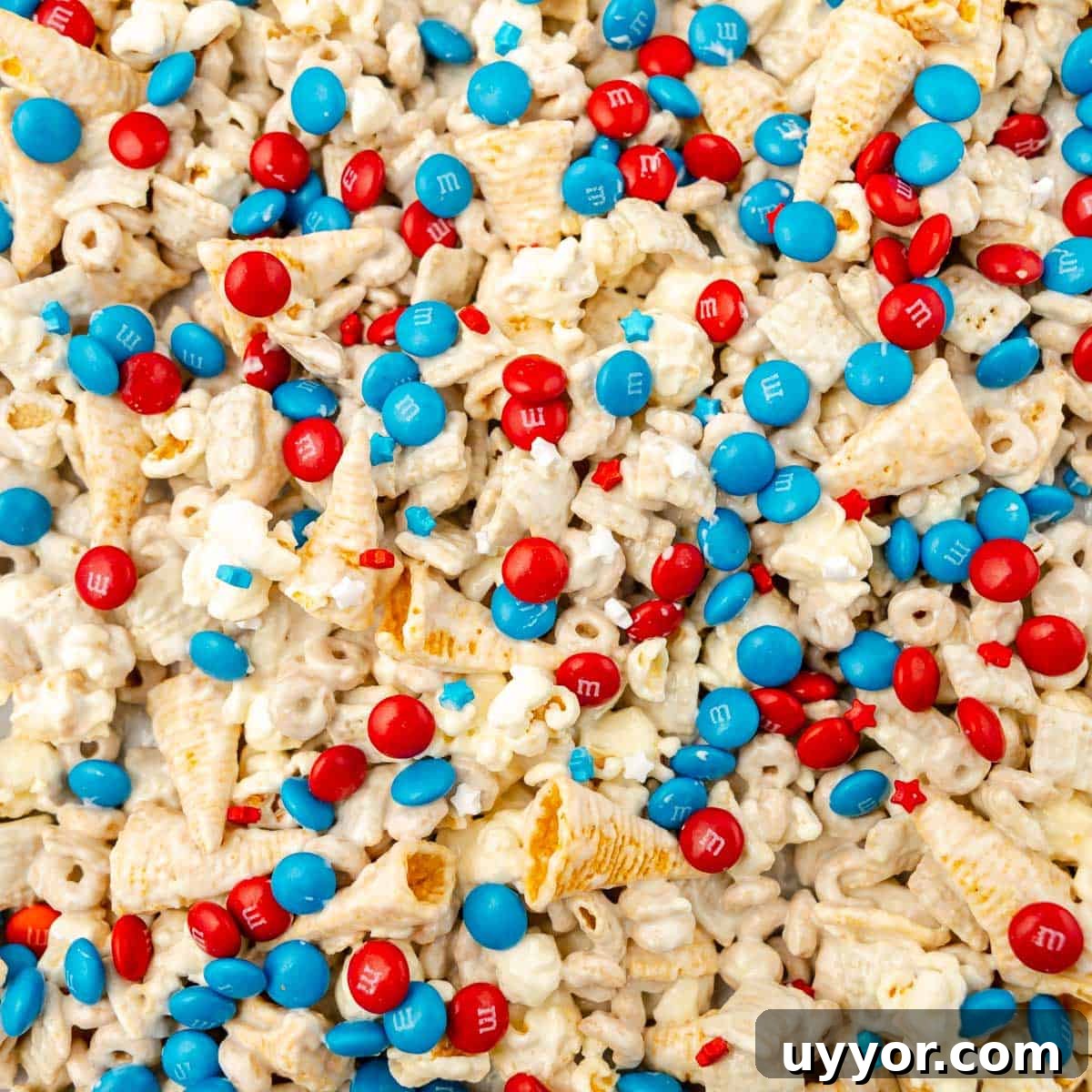Patriotic Red White & Blue Chex Mix Recipe for 4th of July 9 Close-up of a snack mix with popcorn, cereal, small waffle cones, and red and blue candy-coated chocolates, spread out in a random pattern.