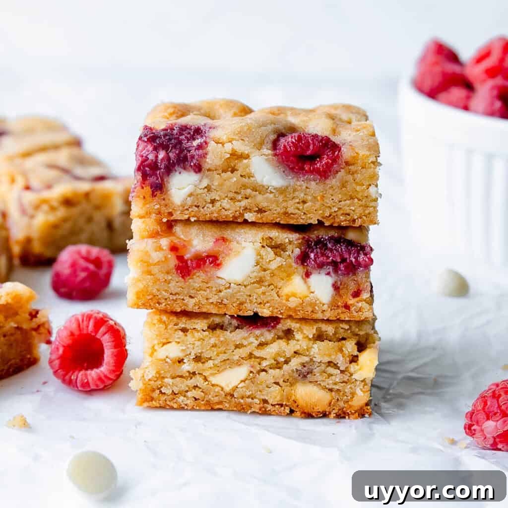 Patriotic Red White & Blue Chex Mix Recipe for 4th of July 10 close up of three stacked raspberry blondies. Blondies and raspberries in the background.