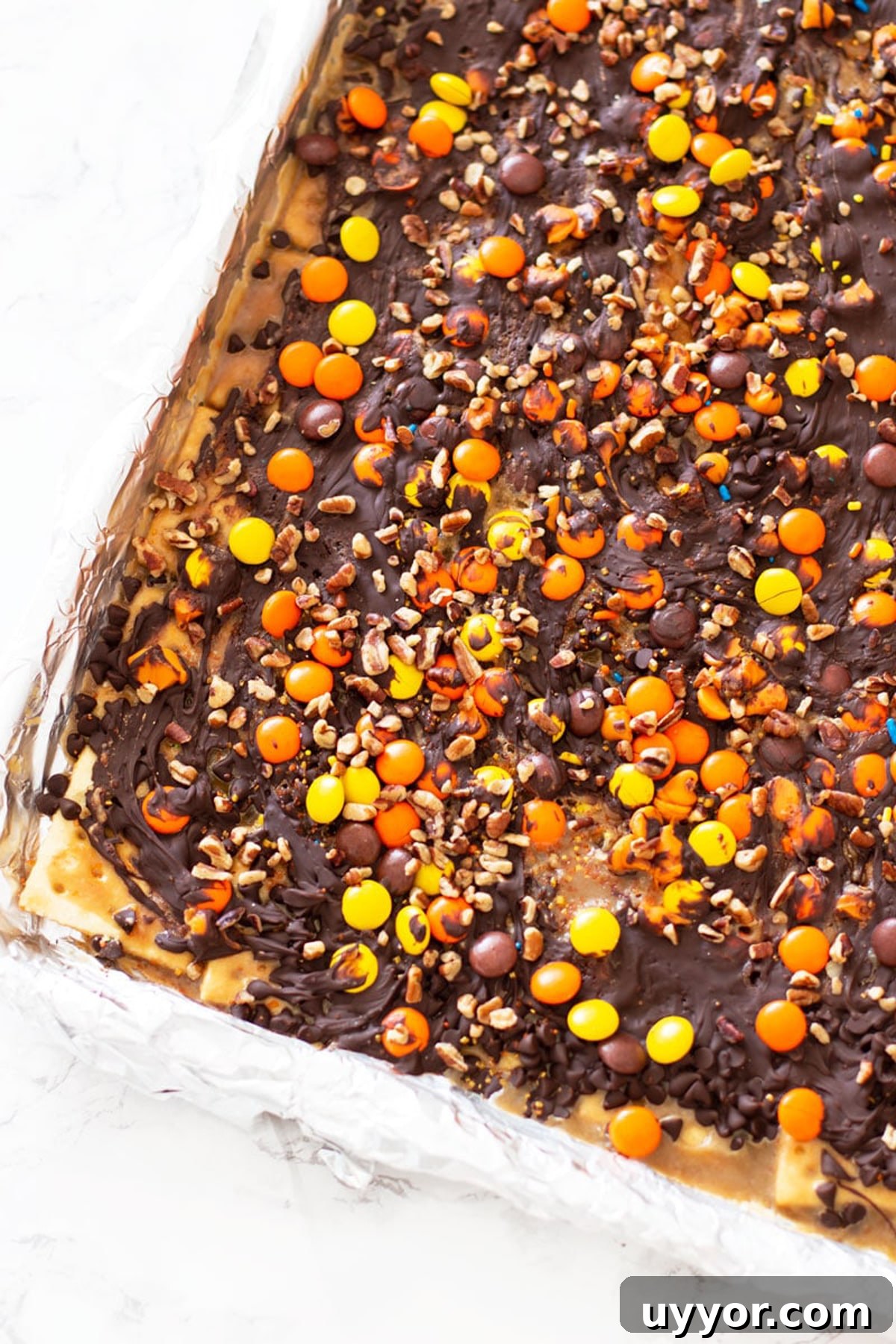 Halloween Crack Candy Recipe: Sweet & Crunchy Toffee Treat 13 Cookie Sheet with Halloween Candy Bark topped with Reese's pieces, chocolate and pecans.