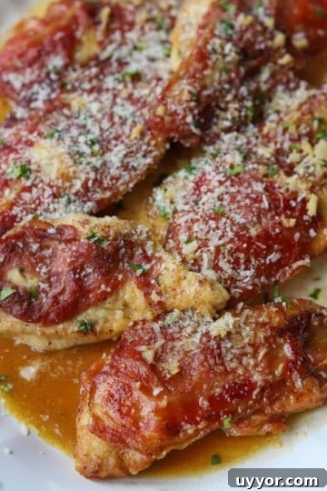 chicken prosciutto on serving plate topped with parmesan cheese
