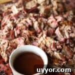 How to Smoke a Pork Butt for Tender, Flavorful Pulled Pork 18 Pulled pork shredded on a cutting board with a side of bbq sauce.