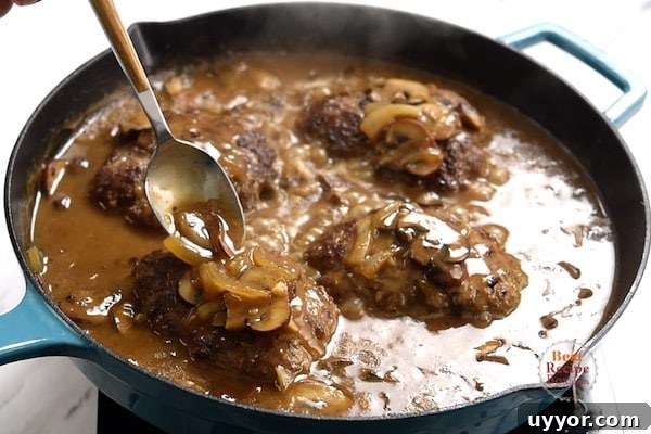 Salisbury Steak with Savory Mushroom and Onion Gravy 10 Pouring gravy over the top of the beef patties