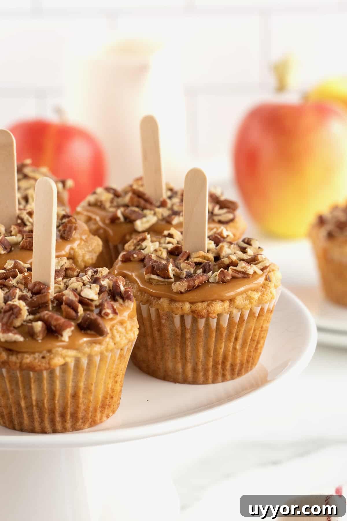 Caramel Apple Cupcake Recipe with Brown Butter Streusel 4 Caramel apple cupcake with caramel and pecan pieces on top and popsicle sticks in the centers.