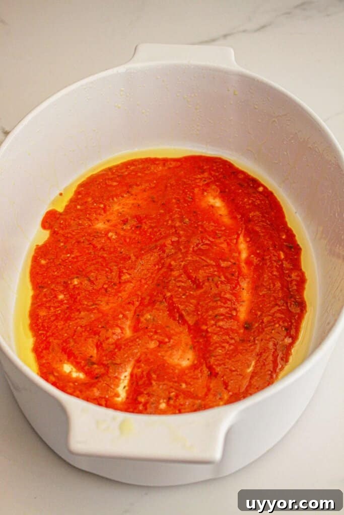 Classic Homemade Eggplant Parmesan Recipe for Crispy Layers 7 Sauce being spread into the bottom of a baking dish.