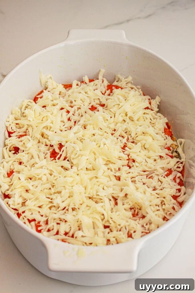 Classic Homemade Eggplant Parmesan Recipe for Crispy Layers 9 Shredded cheese on top of sauce in a baking dish.